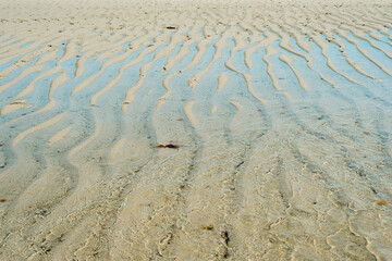 Water and sand create a wave texture during low tide.
