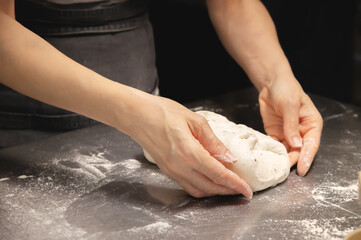 Women's hands carry out actions with raw bread. Dough before dipping into a bakery oven