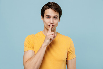 Young secret man 20s wearing yellow t-shirt say hush be quiet with finger on lips shhh gesture...
