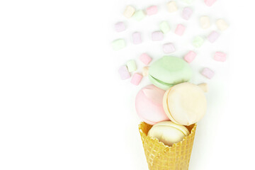Yellow waffle cone with green, pink and yellow marshmallows looks like macaroons, celebration and entertainment concept.