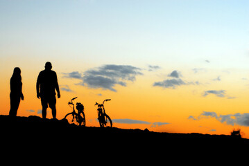 Fototapeta na wymiar couple on the sunset with bikes landscape