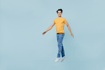 Full body smiling happy cheerful fun satisfied young man 20s wear yellow t-shirt jump high look...