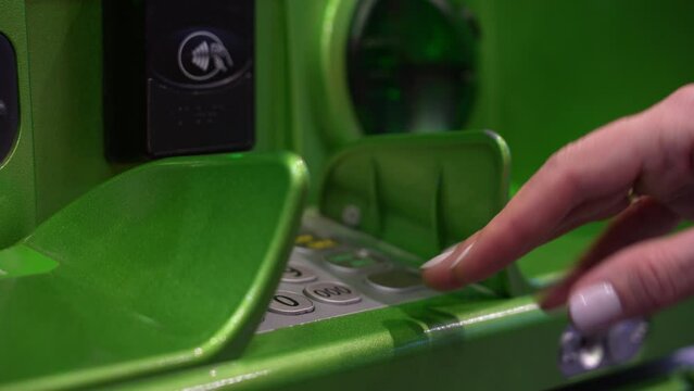 Unrecognizable woman using ATM machine. Inserting card in cash machine. Inserting credit debit card in cash dispenser. Hand entering personal identification number on ATM. 
