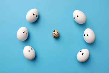 A quail egg surrounded by chicken eggs. Rejection of non-ordinary people in society