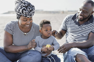 Happy african family having playful time together on the beach at summer vacation - Parents and...
