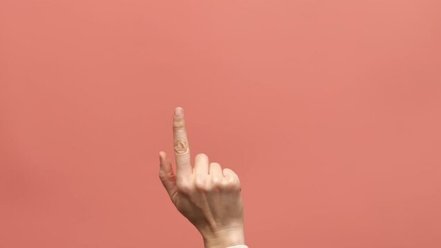 Female hand finger touching, clicking, tapping, sliding on pink background as looks like using smartphone, digital tablet or touchscreen device