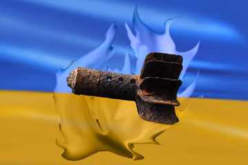 A mortar shell against the background of the Ukrainian yellow-blue flag on fire