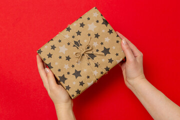 person holding a gift box top view, on a red background