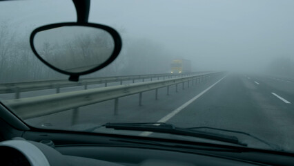 View through windshield from driving auto in highway on foggy day.Poor road visibility.Cloudy gray...