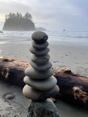A cairn formation on the beach with an island in the background