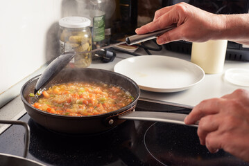 Prepared from a sauté onion, tomato and pepper for a paella, in the kitchen of a house.