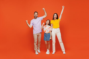 Fototapeta premium Full size young cool happy parents mom dad with child kid daughter teen girl wear basic t-shirts doing winner gesture celebrate isolated on yellow background. Family day parenthood childhood concept