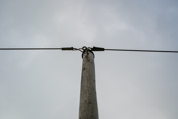 View of the top of a wooden electricity pole with connected power lines
