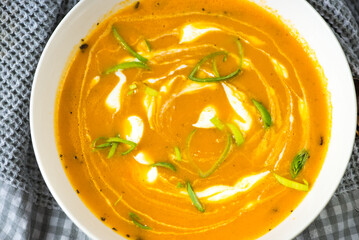 Pumpkin soup wih circle from cream, leek shoot, decorative surface .