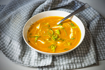Pumpkin soup in plate on checkered towel.
