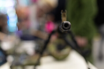 The muzzle with the sight of an army assault rifle is pointed at the camera. Close-up of the weapons, background blurred., Copyspace