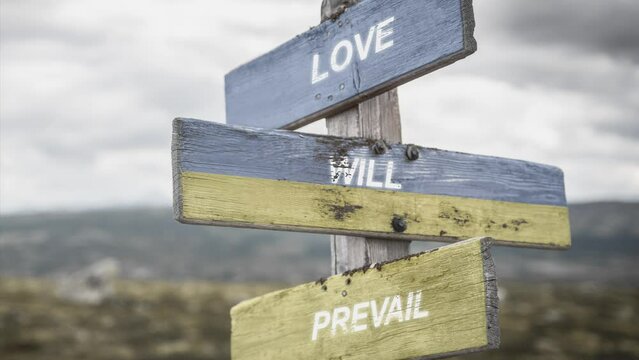 love will prevail text quote on wooden signpost outdoors, written on the ukranian flag.