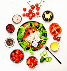 Greek salad with feta cheese, olives, cherry tomato, paprika, cucumber and red onion, healthy vegeterian mediterranean diet food, low calories eating. White stone background, top view