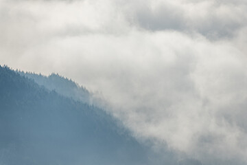 Silhouette of mountains in the mist above the sea of fog in winter.