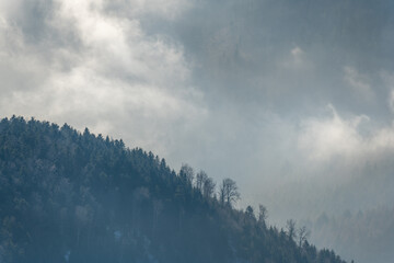 Silhouette of mountains in the mist above the sea of fog in winter.