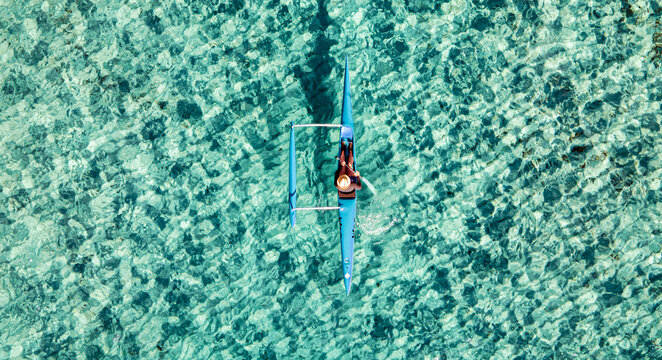 Un canoé polynésien navigue dans une eau turquoise d' une plage de Ramatuelle dans le Golfe de Saint-Tropez