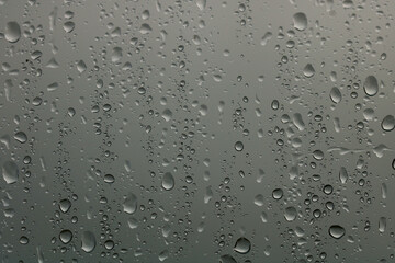 Rain drops on a window with a stormy sky background. Focus is on the drops. A wintery image.