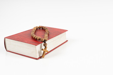 Closeup of wooden Christian cross necklace next to holy Bible with copy space