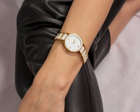 classic white women's watch in a golden frame on a woman's hand.