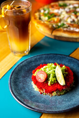 Olivier salad with red caviar in a beautiful serving on a blue plate at sunset