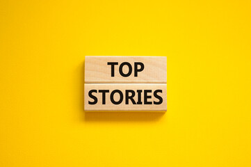 Top stories symbol. Concept words Top stories on wooden blocks on a beautiful yellow table yellow background. Business story and top stories concept, copy space.