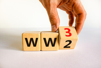 WW3 world war 3 symbol. Businessman turns the wooden cube and changes the concept word WW2 to WW3. Beautiful white table white background, copy space. Business WW3 world war 3 concept.