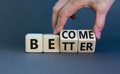 Become better symbol. Businessman turns wooden cubes and changes the concept word Better to Become. Beautiful grey table grey background. Business become better concept. Copy space.