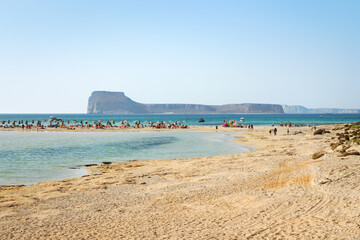 Tourists on the famous Balos beach, with Gramvousa island in the background