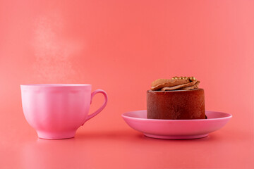 chocolate cake on a pink saucer with a pink cup on a pink background