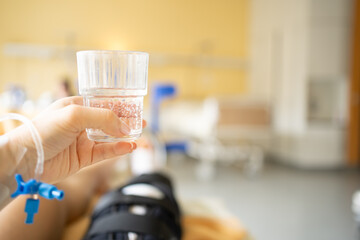 Hand mit einem Glas Wasser im Krankenhaus Bettruhe
