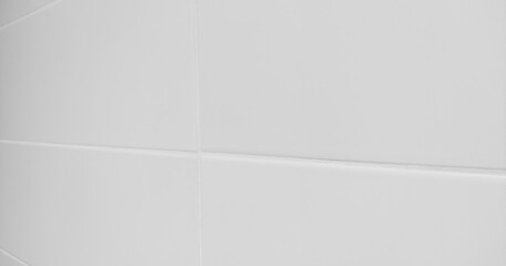 White background, sloping view of the wall with white tiles close-up. Soft focus