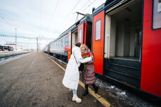 girls say goodbye hugging on the station platform