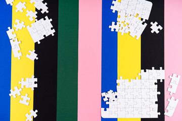 Missing jigsaw puzzle pieces. Business concept. Fragment of a folded white jigsaw puzzle and a pile of uncombed puzzle elements against the background of a colored surface.