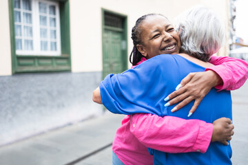 Multiracial senior women hugging each other - Elderly diverse community concept - Focus on african...