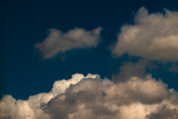 back-lit cumulus clouds, shaded in gray, framing a dark blue sky.