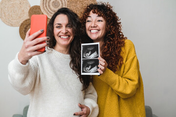 Happy gay couple of women holding ultrasound photo scan on video call - Growing baby in pregnancy...