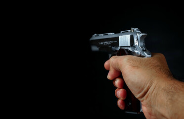 Male hand holding a gun on black background . A gun in a man's hand. defense or attack murderer or armed robber, First person view of a pistol.                              