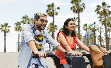 Happy friends having fun riding electric bike outdoor at the beach - Focus on hipster man face