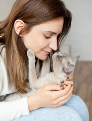 Close-up portrait of a beautiful young woman with a cute  cat at home. Female hugging her cute domestic pet.