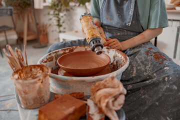 Woman crafter making clay dish in pottery room