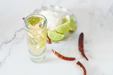 Lime slice falls into a glass with mexican tequila