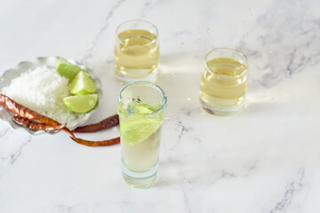 Lime slice falls into a glass with mexican tequila