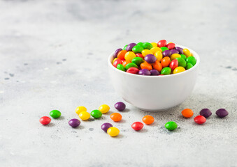 Multicolored mix of fruit candies in white bowl on light background. © DenisMArt