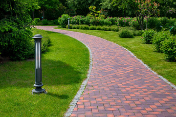 iron ground lantern garden lighting of park curved path paved with stone tiles in park among...