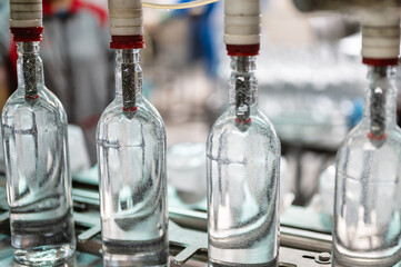 Equipment pours vodka into glass bottles on production line